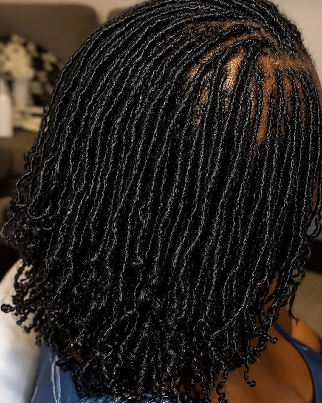 A finished set of microlocs seen from behind, hundreds of fine locs falling to shoulder length with coiled ends